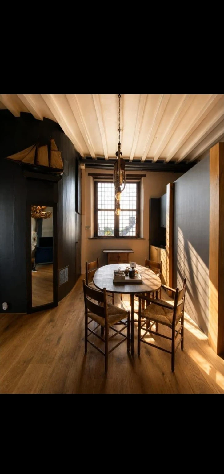 Zithoek van de TorenSuite met houten tafel, stoelen en balkenplafond
